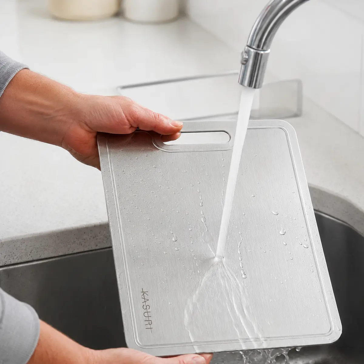 Kasuri titanium cutting board being washed at a kitchen sink