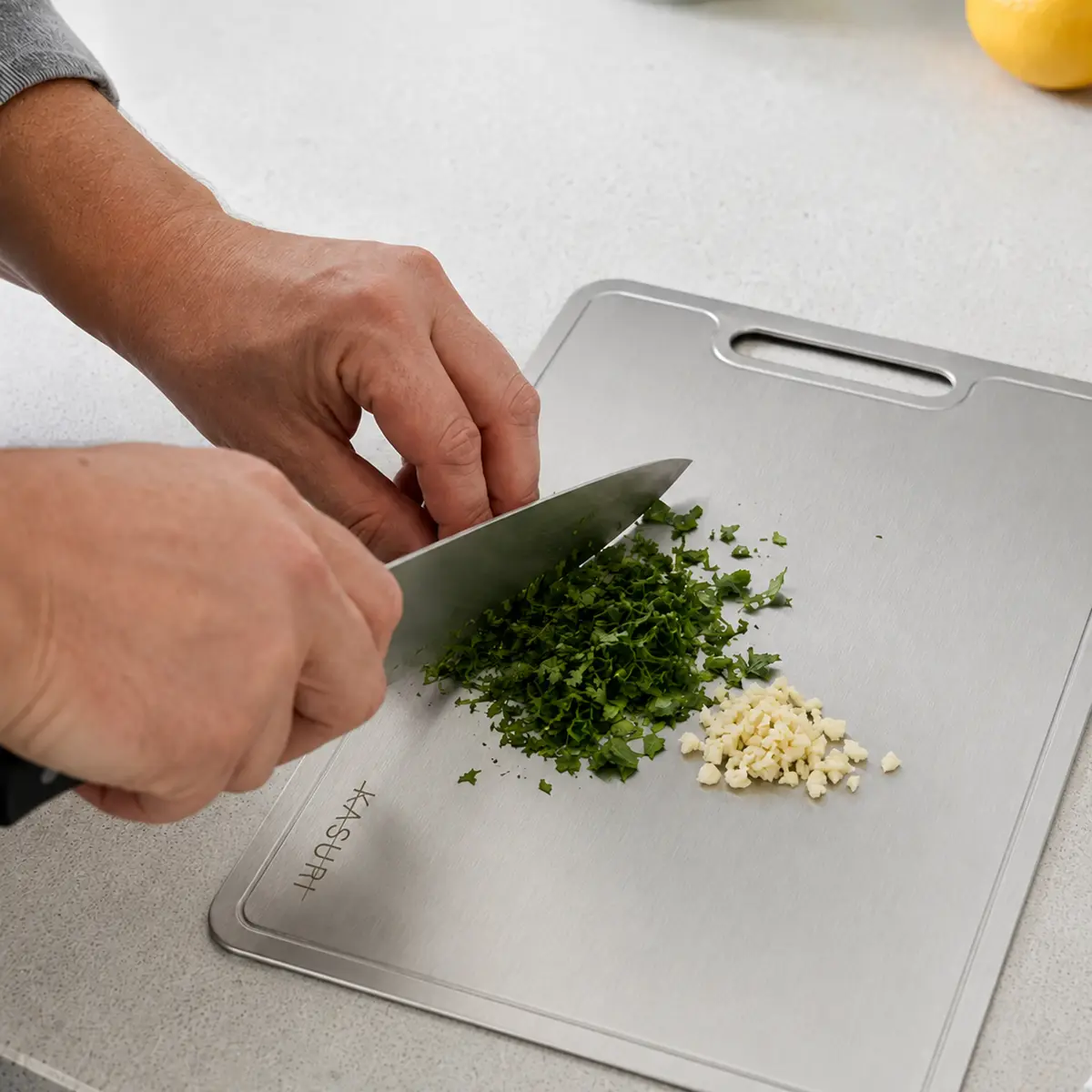 Fresh herbs and garlic being chopped on a Kasuri cutting board