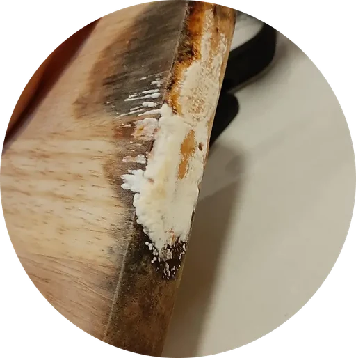 Worn wooden cutting board with residue along the edge